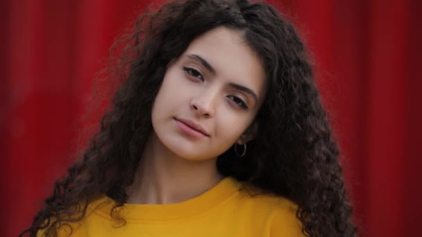 Schattige tiener meisje close-up portret op mode gele trui, rode muur achtergrond — Stockvideo
