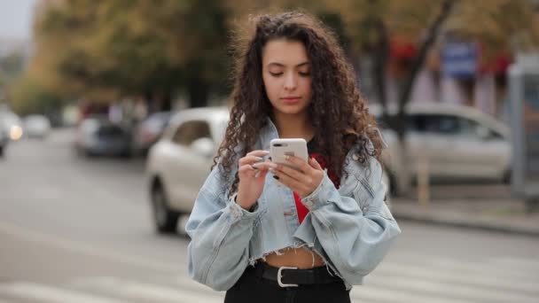 Menina adolescente usando mensagens de navegação de mensagens de smartphone um telefone celular, se comunicar na cidade — Vídeo de Stock