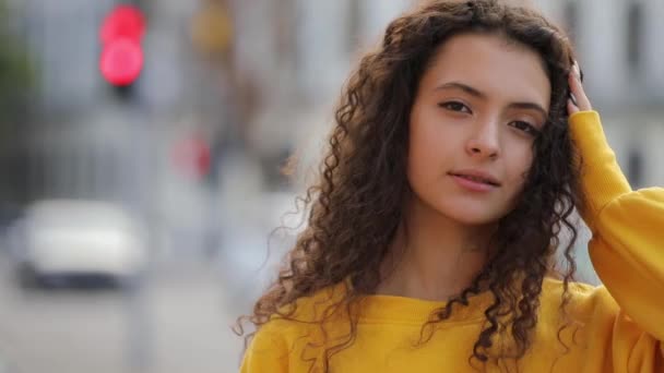 Söta lockigt tonåring flicka i gul ledartröja, urbana staden bakgrund — Stockvideo