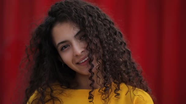 Schattige tiener meisje lachen in mode gele trui, rode muur achtergrond — Stockvideo