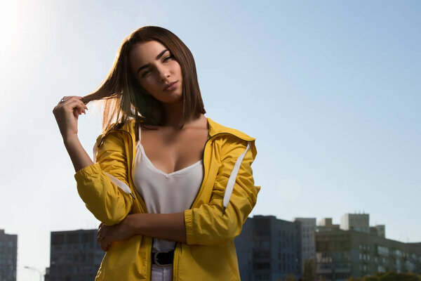 Pretty woman outdoor portrait at sky background in yellow windbreaker