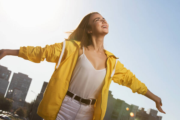 Happy woman enjoying freedom outdoor on sky background with raised hands