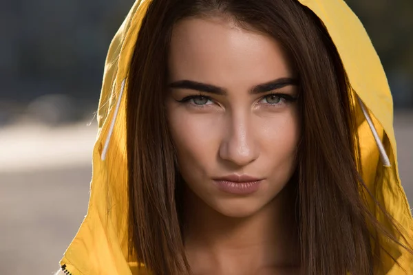 Confident serious woman outdoor portrait under yellow hood
