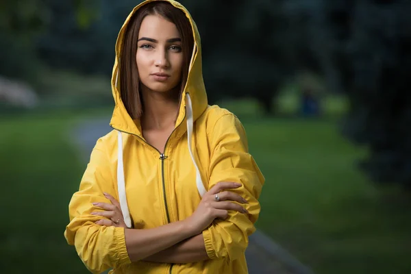 Woman wear yellow raincoat with hood in park