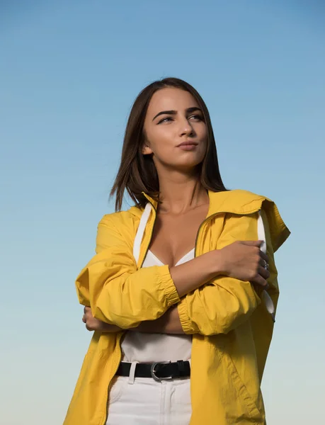 Woman in yellow raincoat over blue sky background