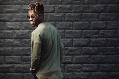 Duvara karşı ayakta cool adam giyim kazak elbise