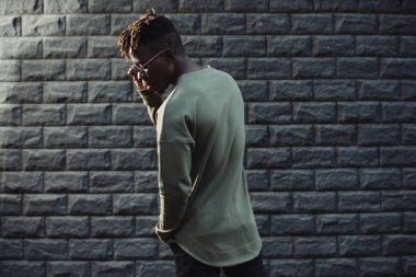 Tuğla duvar arka plan karşı şık kazak elbise giyen adam