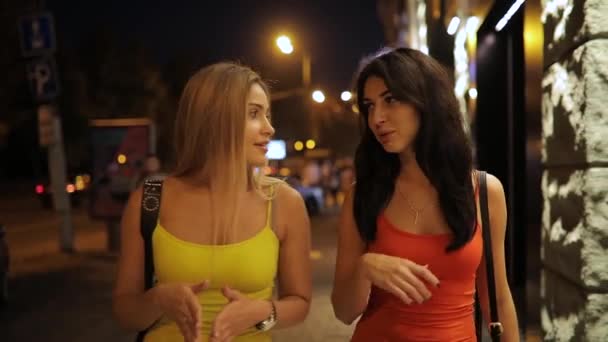 Mujeres jóvenes amigas caminando y hablando en la calle de la ciudad nocturna — Vídeos de Stock