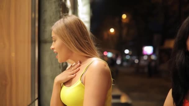 Mujer joven adicta a las compras emocionada mirando escaparate de la tienda en la calle de la ciudad de noche — Vídeos de Stock