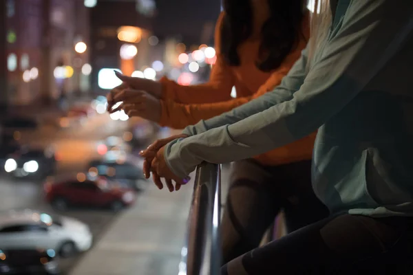 Закрытие женских рук, опирающихся на террасу в ночном городе — стоковое фото