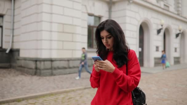 Frau läuft mit Smartphone-App durch die Stadt, Steadicam fliegt um sie herum — Stockvideo