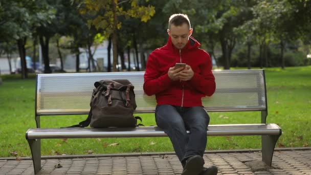 Молодой Человек Заканчивает Работу Над Мобильным Телефоном Парке Отдыхает — стоковое видео