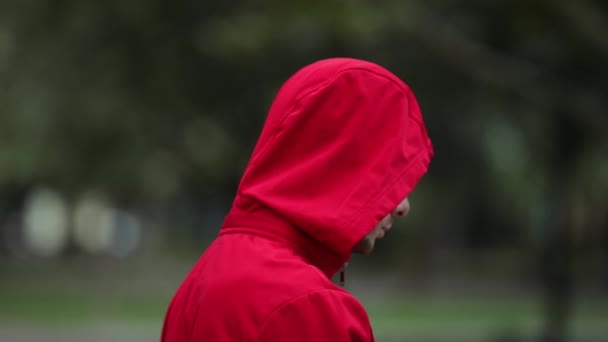 Hombre Capucha Roja Brillante Girando Cara Mirando Cámara — Vídeos de Stock