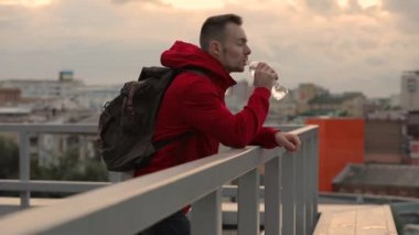 Yorgun bir adam içme suyu ayakta cityscape için seyir terasında