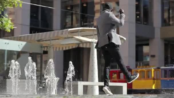Счастливый веселый африканский бизнесмен танцует в городе — стоковое видео
