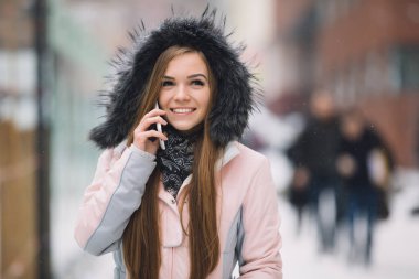 Karlı kış gününde akıllı telefon mobil cihaz kullanan genç kadın