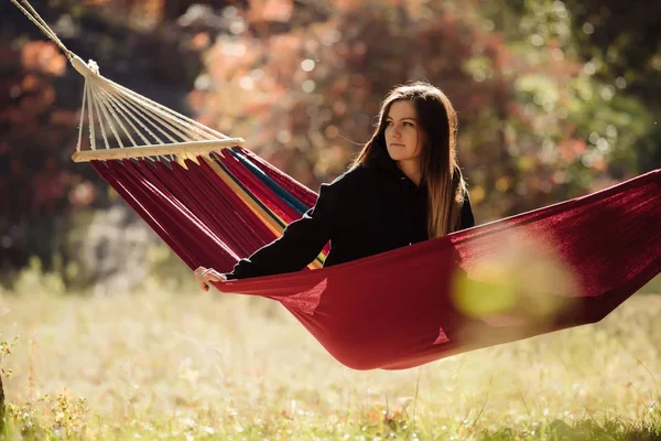黄金の秋の日のハンモックに座って休んでいる女性 — ストック写真