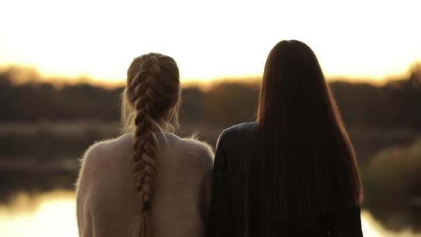 Calma, escena tranquila, vista trasera de las mujeres amigas relajándose y mirando el río después del atardecer, acercar — Vídeos de Stock