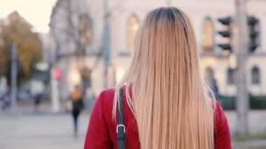 Kırmızılı çekici kadın şehirde yürüyüş elbise ve geri görünüyor