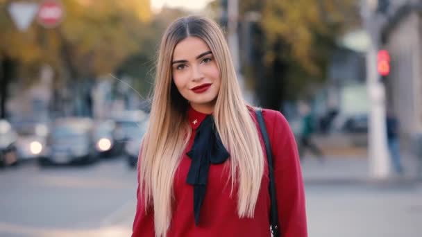 Sexy senhora carismática em vestido vermelho andando ao longo da rua olhando para mim — Vídeo de Stock