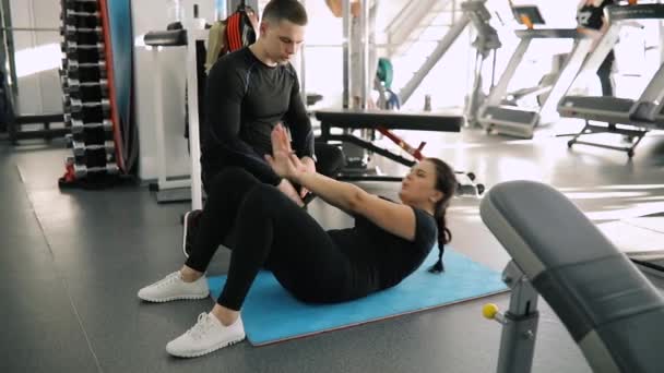Bir acemi spor kadın o göbek pompalama sırasında spor salonunda eğitim kişisel fitness eğitmeni — Stok video