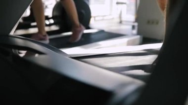 Spor salonunda koşu bandı üzerinde çalışan bacaklar