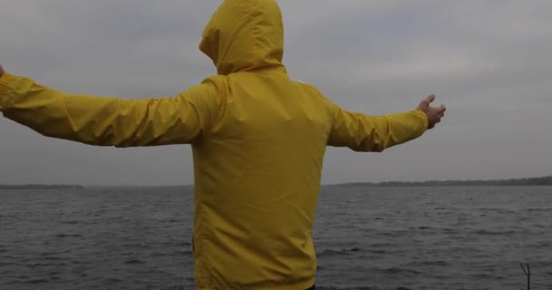 Liberdade, homem de casaco amarelo com as mãos levantadas, visão traseira — Vídeo de Stock