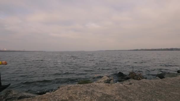 Senderismo viajero hombre en chaqueta amarilla corriendo solo al aire libre en el río, clima nublado, cámara lenta — Vídeo de stock