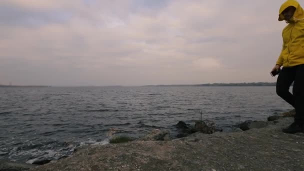 Yalnız nehirde açık yürüyüş sarı ceketli adamı gezgin hiking, bulutlu hava — Stok video