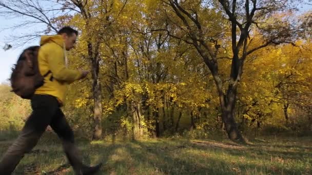 Homme en veste jaune marchant avec smartphone dans la forêt d'automne 