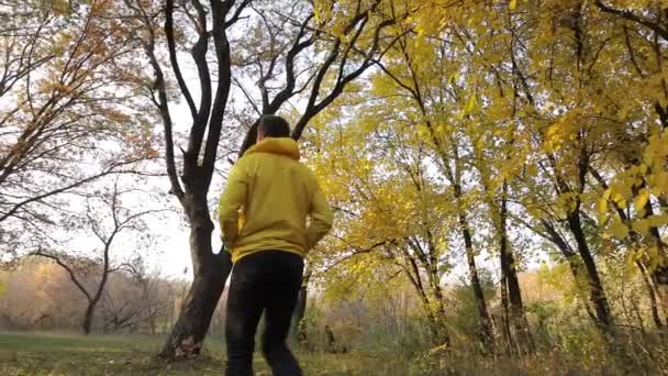 Homem de casaco amarelo andando na floresta de outono — Vídeo de Stock