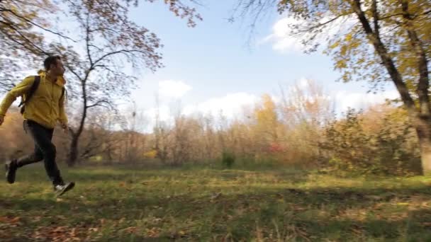 Счастливчик в желтой куртке бегает по осеннему лесу — стоковое видео