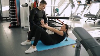 Bir acemi spor kadın o göbek pompalama sırasında spor salonunda eğitim kişisel fitness eğitmeni