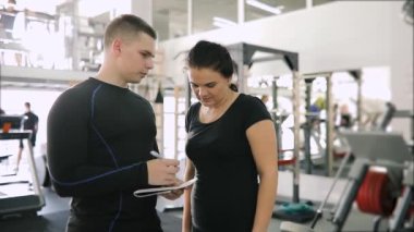 Kişisel fitness eğitmeni defterini acemi kadın içinde jimnastik salonu için bir planı yazma