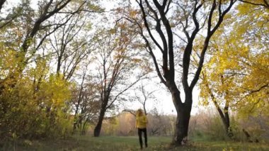 Mutlu adam sarı ceketli sonbahar ormanda koşmak