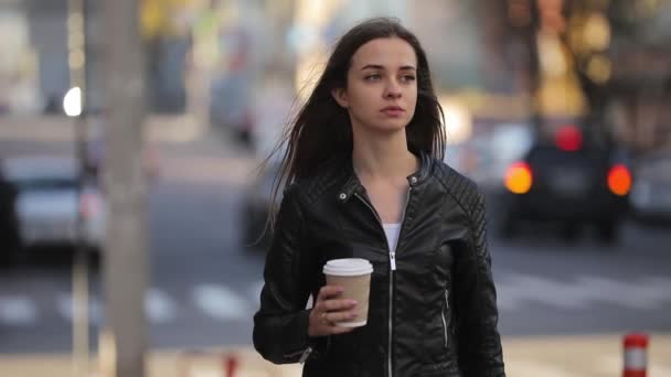Mooie vrouw houden papier koffie kopje en genieten van een wandeling in de stad, slow-motion — Stockvideo