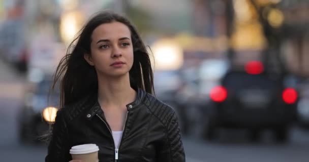 Hermosa mujer sosteniendo una taza de café de papel y disfrutando de un paseo por la ciudad — Vídeos de Stock