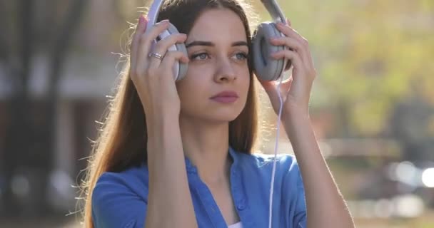Милая женщина слушает музыку на открытом воздухе в наушниках — стоковое видео