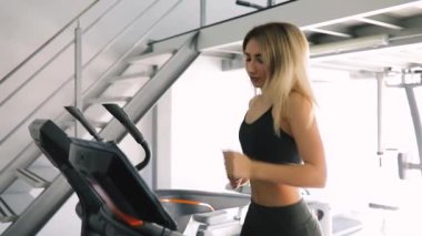 Spor salonu fitness Club bir koşu bandı üzerinde çalışan genç kadın