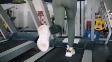 Spor salonunda bir koşu bandı üzerinde çalışan arka görünümü kadın