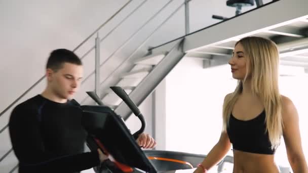 Joven instructora de fitness entrenando a una mujer mientras corre en la cinta de correr — Vídeos de Stock