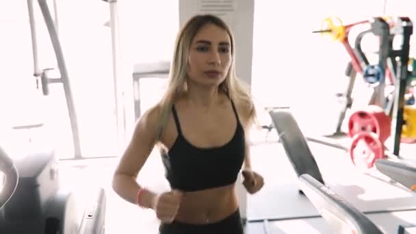 Jonge vrouw lopen op een loopband in de sportschool fitnessclub — Stockvideo