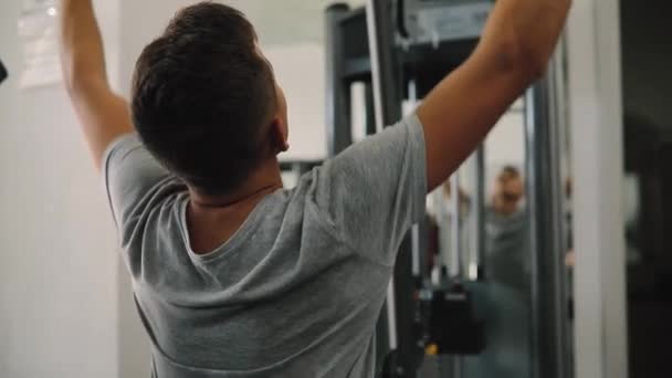 Jonge beginner man uitoefenen in gym training met de apparatuur van de opleiding — Stockvideo