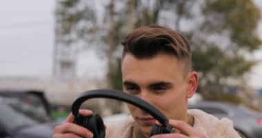 Şehirde kulaklık müzik dinleme genç adam koyar