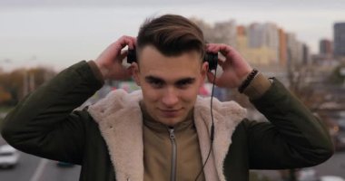 Şehirde kulaklık müzik dinleme genç adam koyar