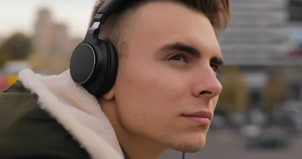在城市用耳机听音乐的年轻人 — 图库照片