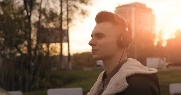 Man enjoying music walking in sunset city with headphones