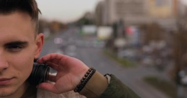 Genç adamın şehirde kulaklıklarla müzik yarım yüz