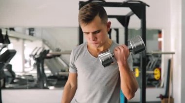 Genç acemi adam dumbbells ile fitness Center'da pazı pompalama