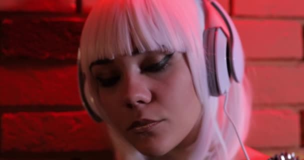 Beyaz Peruk Kulaklıklar Kırmızı Işık Tuğla Duvar Kullanarak Müzik Olağandışı — Stok video